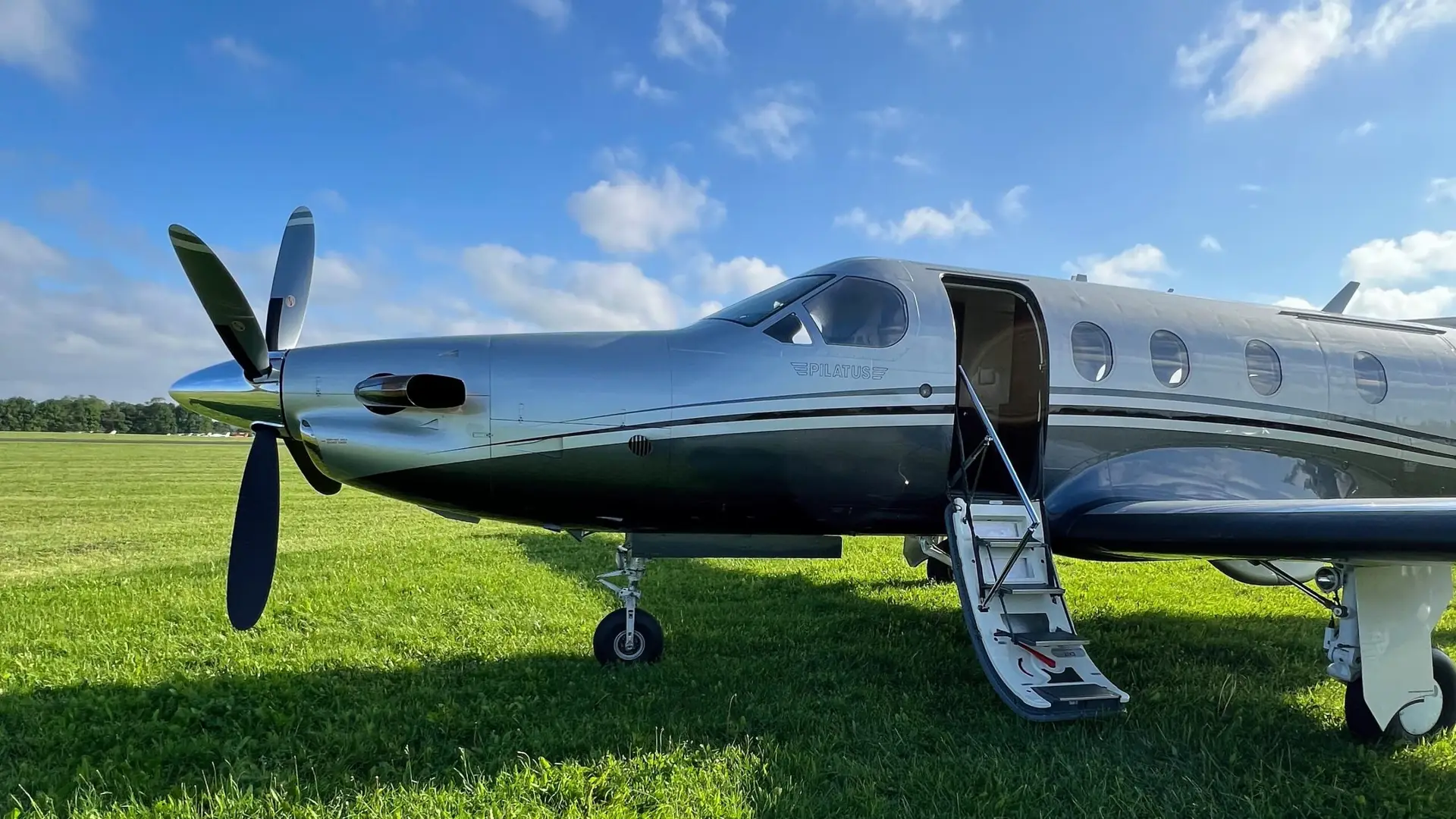 Pilatus aircraft parked on green grass under blue sky